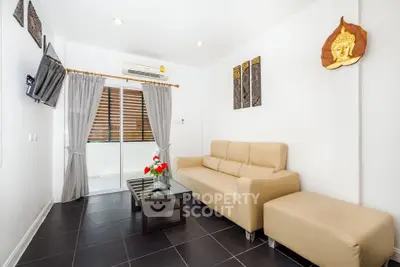 Modern living room with beige sofa, wall-mounted TV, and balcony access in a stylish apartment.