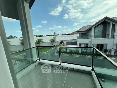 Modern balcony with glass railing offering a serene neighborhood view.