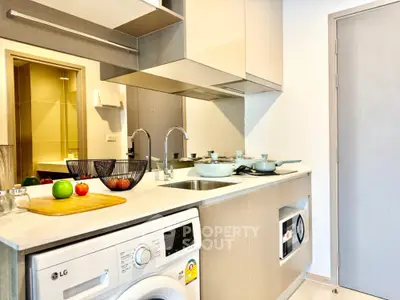 Modern kitchen with sleek appliances and washing machine, featuring a minimalist design and open layout.