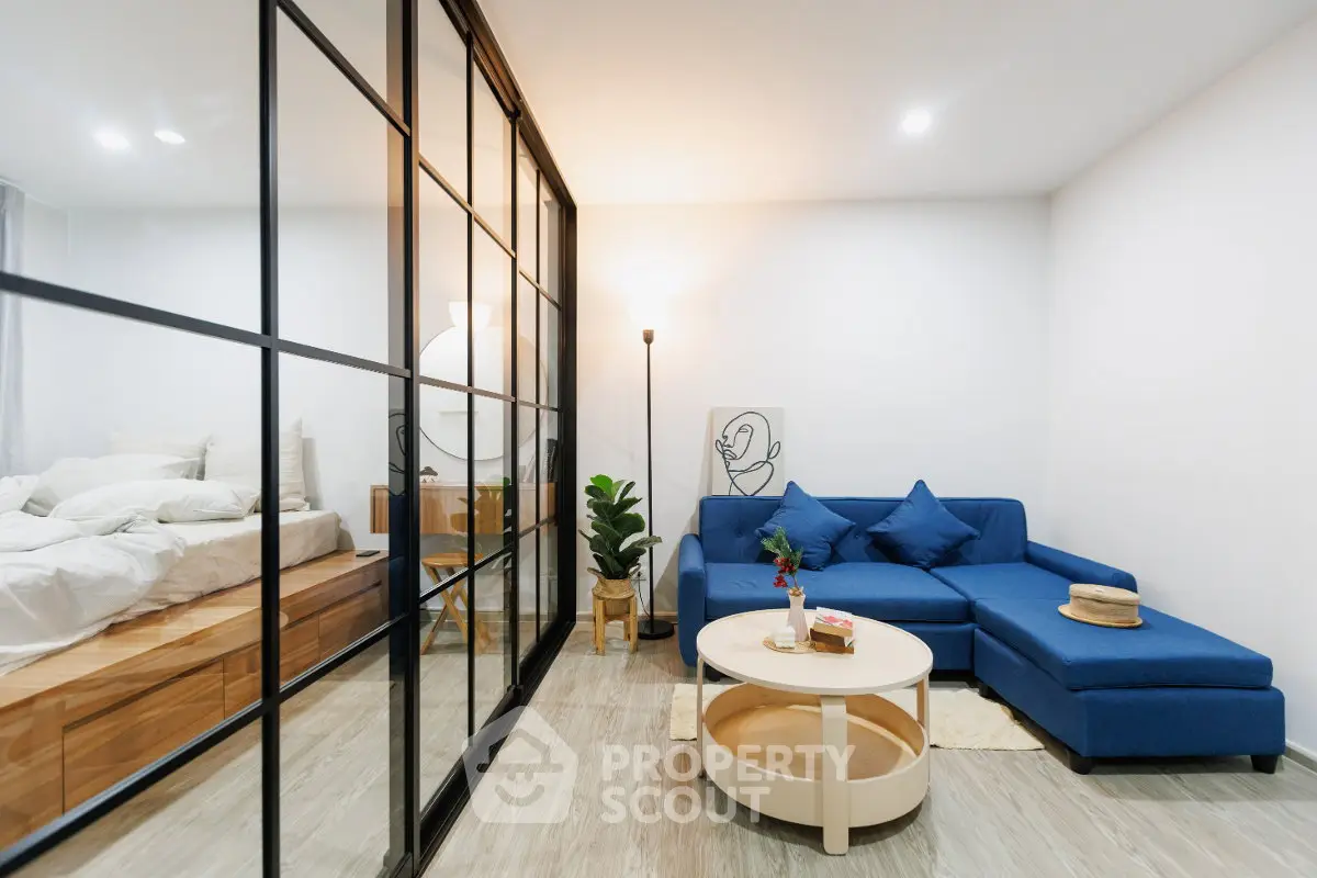 Modern living room with glass partition, blue sofa, and stylish decor