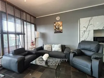 Modern living room with sleek black furniture and large windows for natural light.