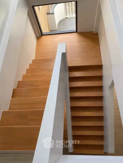 Modern wooden staircase with sleek white railings in a contemporary home interior.