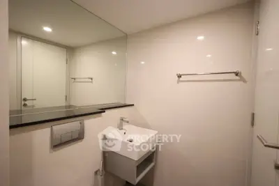 Modern bathroom with sleek sink and large mirror in a contemporary apartment.