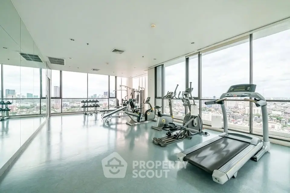Spacious gym with panoramic city views and modern fitness equipment.