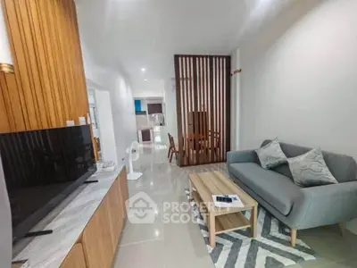 Modern living room with stylish decor and open layout, featuring a cozy sofa and sleek TV setup.