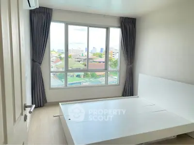 Bright bedroom with large window and city view, featuring a modern bed frame and elegant curtains.