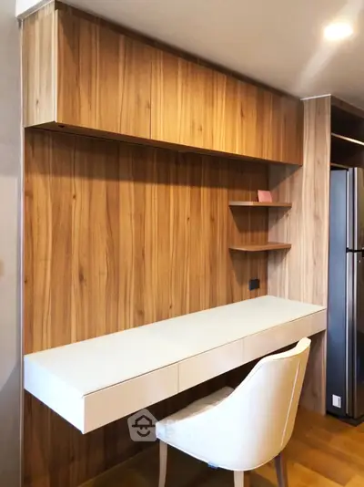 Modern study nook with wooden paneling and sleek white desk in a stylish apartment.