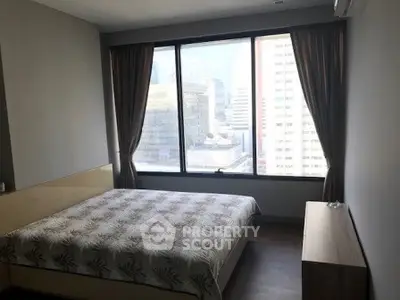 Spacious bedroom with large window offering stunning city views in modern apartment.
