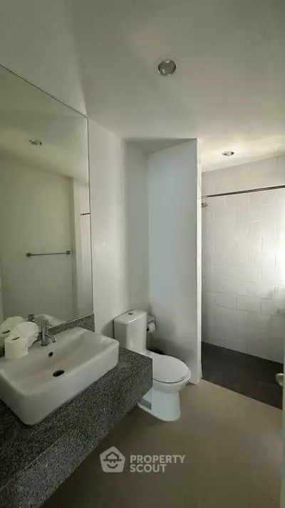 Modern bathroom with sleek design featuring a granite countertop and spacious shower area.