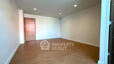 Spacious empty room with wooden flooring and recessed lighting, perfect for customization.