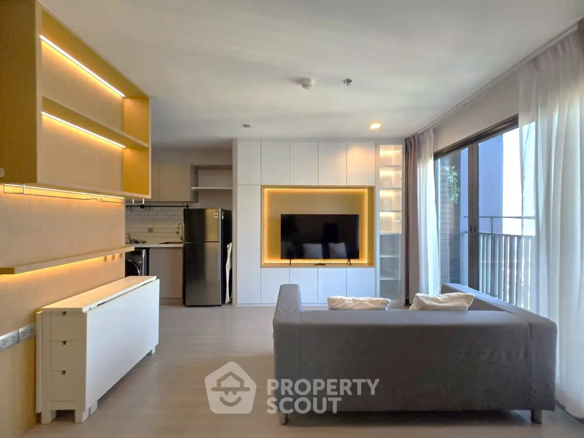Modern living room with sleek design and open kitchen layout, featuring large windows and natural light.