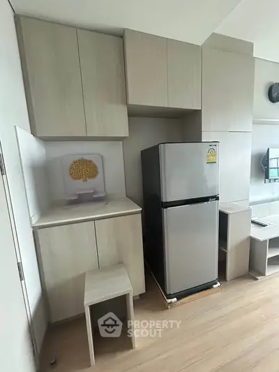 Modern kitchen with sleek cabinetry and stainless steel fridge in a stylish apartment.