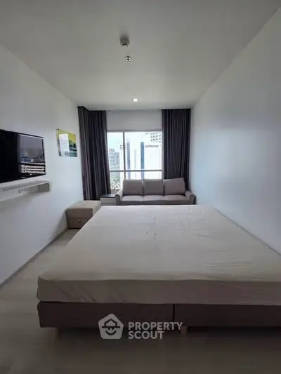 Modern bedroom with large window and city view, featuring a comfortable bed and wall-mounted TV.