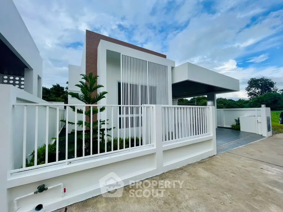 Modern minimalist house exterior with sleek design and lush greenery.