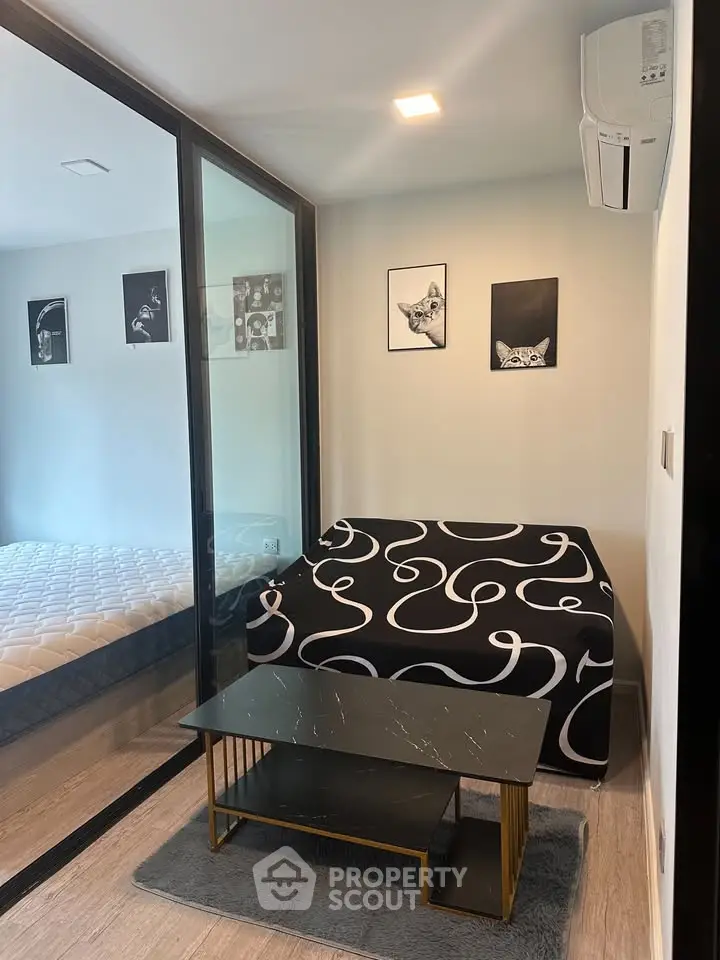 Modern apartment with stylish decor and cozy seating area, featuring a glass partition and chic artwork.