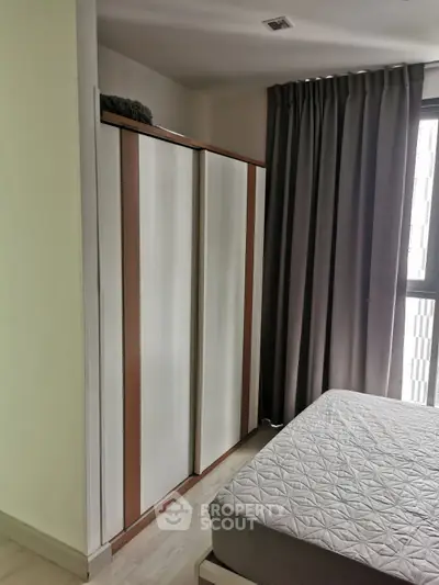 Modern bedroom with sleek wardrobe and cozy bed near large window with curtains.