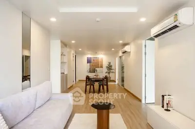 Spacious modern living room with elegant decor and dining area, featuring air conditioning and stylish furniture.