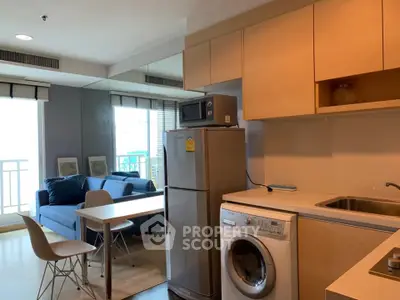 Modern apartment interior with kitchen and living area featuring washing machine and fridge.
