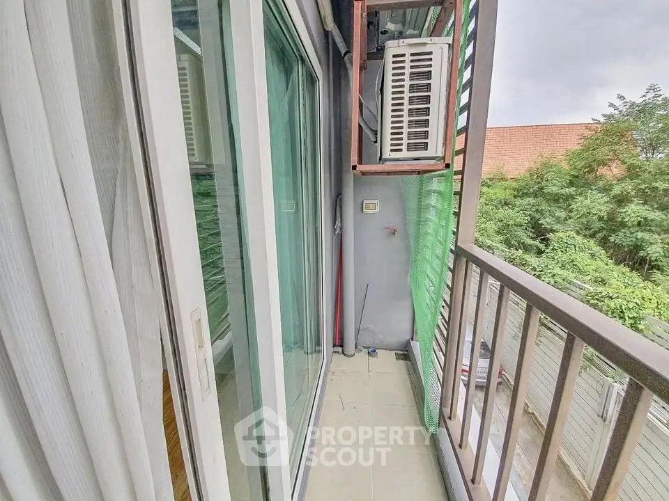Charming balcony with sliding glass doors and lush greenery view, perfect for relaxation.
