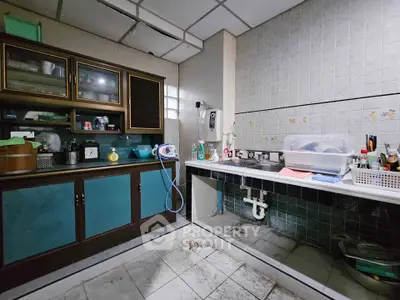 Spacious kitchen with ample storage and tiled backsplash, featuring a sink and countertop space.