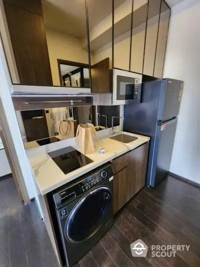 Modern compact kitchen with sleek appliances and dark wood cabinetry