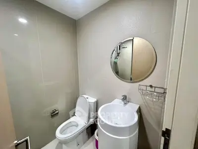 Modern bathroom with sleek fixtures and round mirror, ideal for compact spaces.