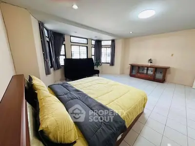 Spacious bedroom with large windows and modern furnishings in a bright apartment.