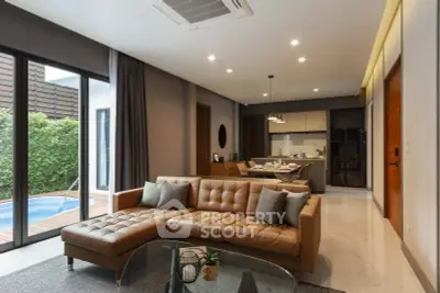 Luxurious open-plan living room with modern kitchen and pool view, featuring elegant furniture and stylish decor.