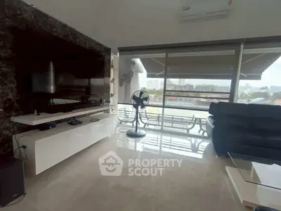 Spacious living room with modern decor and large balcony offering city views.