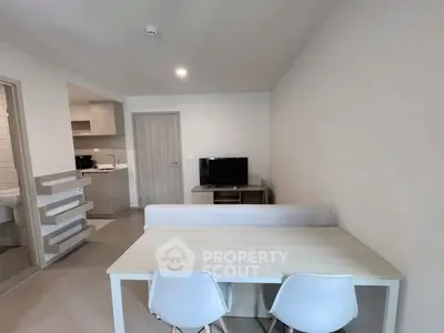 Modern apartment interior with open layout, featuring dining area and cozy living space with TV.