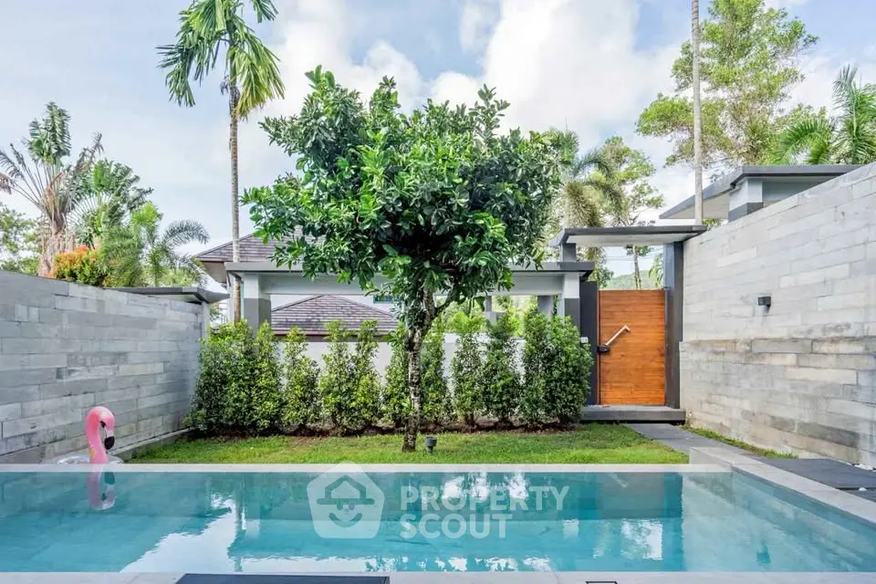 Luxurious private pool with lush greenery and modern stone wall design in a serene backyard setting.