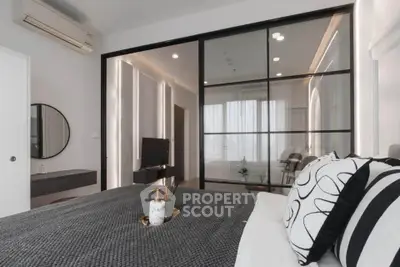 Modern bedroom with stylish decor and glass partition, featuring cozy bedding and elegant lighting.