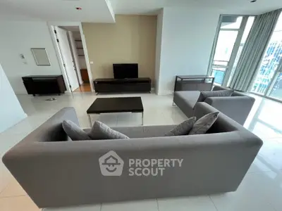 Spacious modern living room with sleek furniture and large windows offering city views.