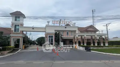 Elegant gated entrance of a residential community with classic architectural design and lush greenery.