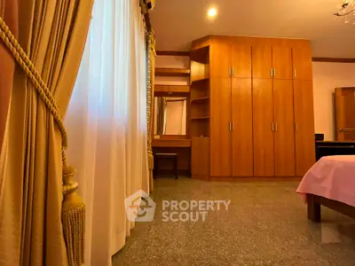 Spacious bedroom with elegant wooden wardrobe and large window with drapes