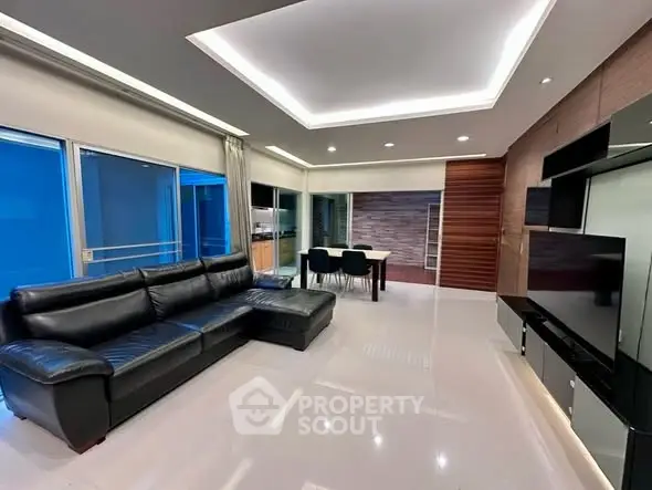 Spacious modern living room with sleek design and large black leather sofa.