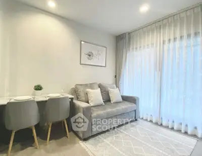 Modern living room with cozy gray sofa and dining area, featuring elegant sheer curtains.
