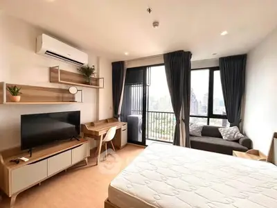 Modern studio apartment with balcony and city view, featuring sleek furniture and ample natural light.