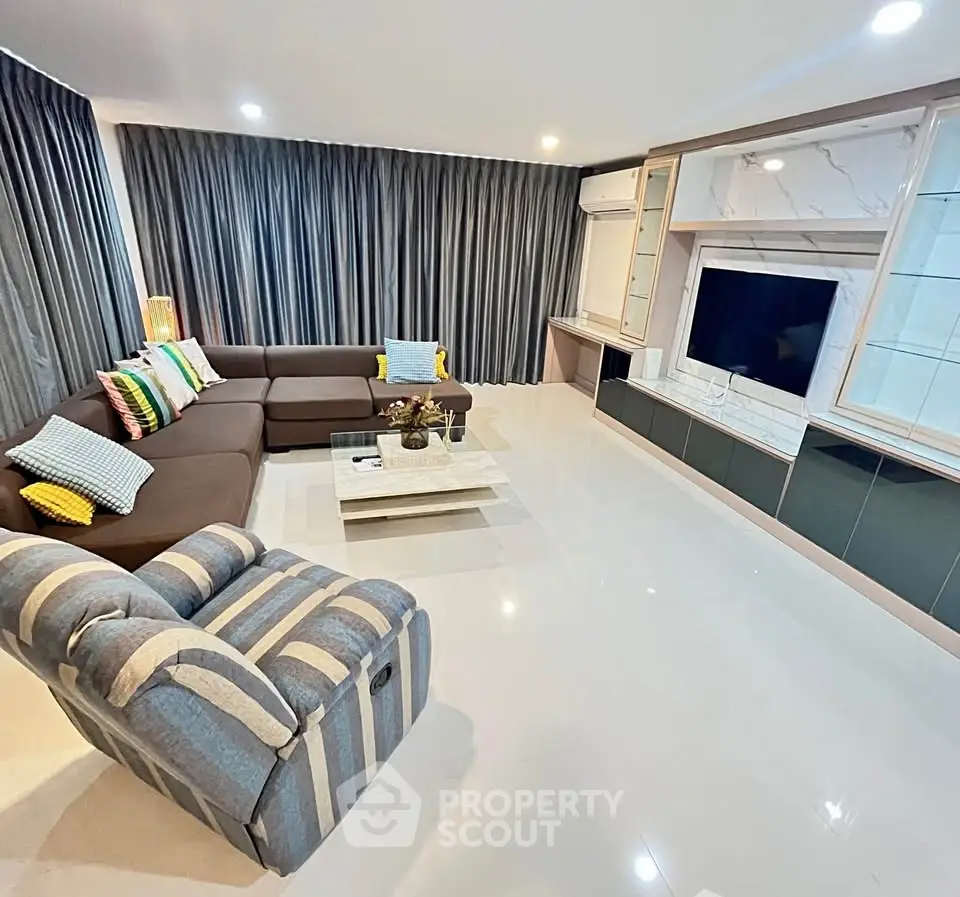 Spacious modern living room with stylish furniture and large TV setup.