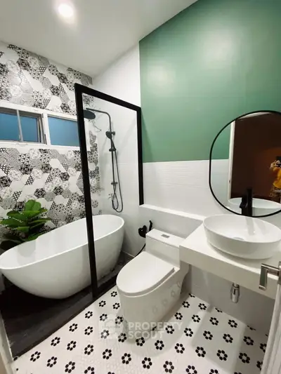 Modern bathroom with stylish bathtub and shower, featuring green accent wall and patterned tiles.