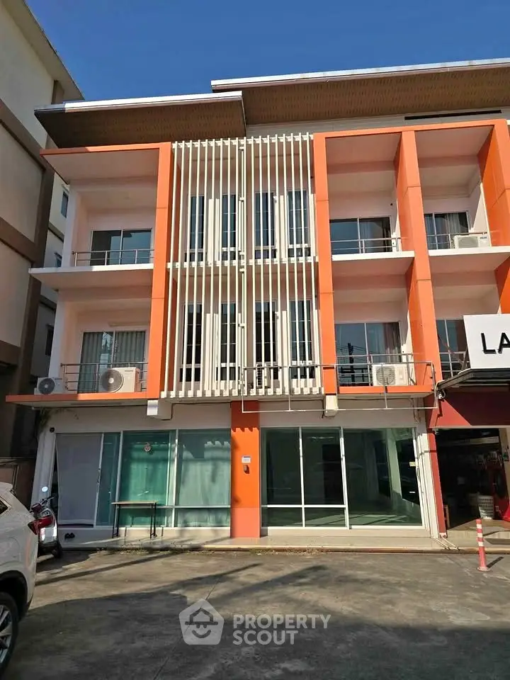 Modern three-story commercial building with orange accents and large windows