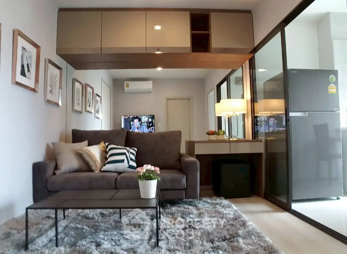 Modern living room with plush sofa, stylish decor, and glass partition leading to kitchen area.
