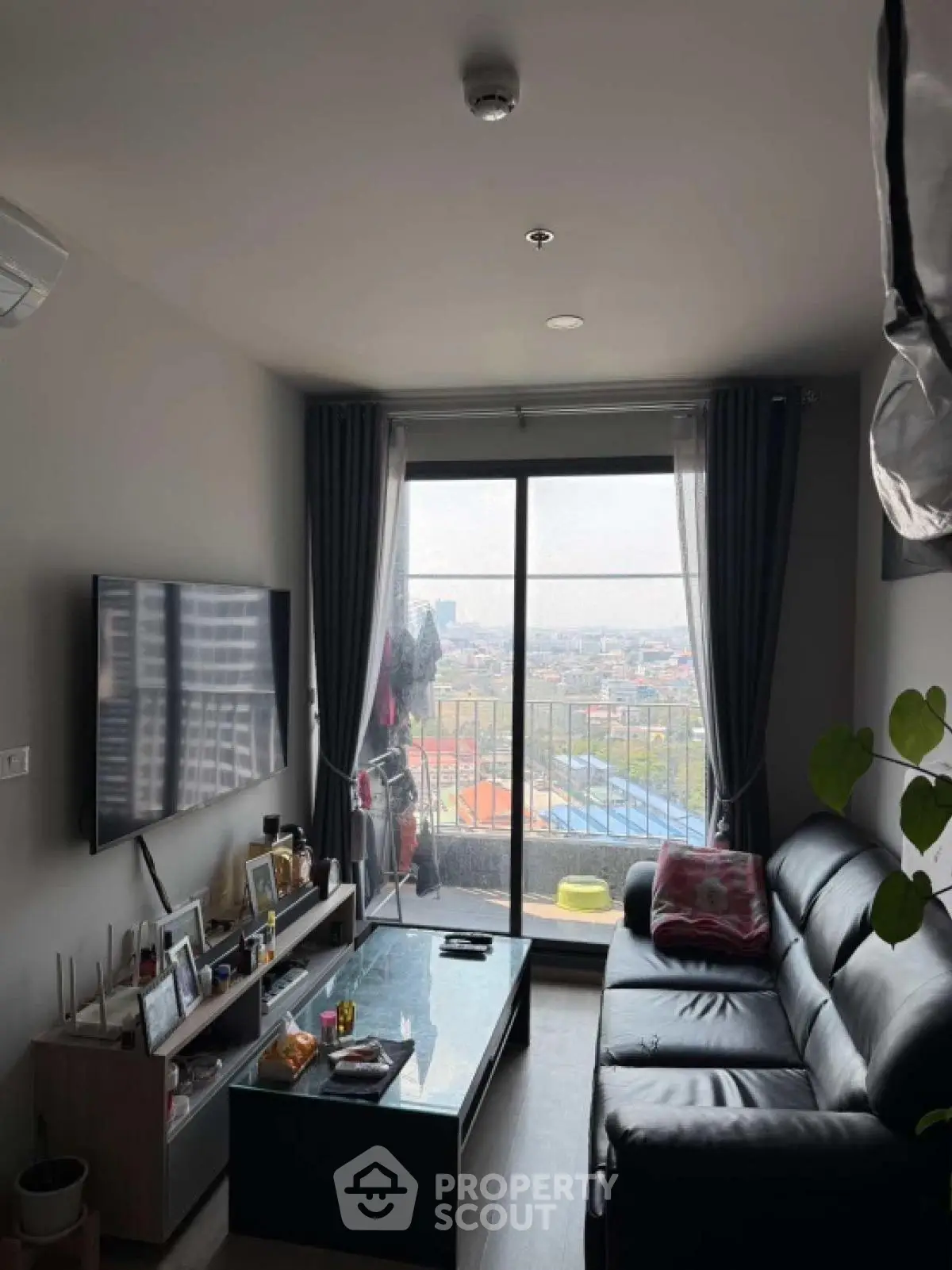 Modern living room with large window offering stunning city view and stylish furnishings.