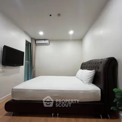 Modern bedroom with sleek design, featuring a plush bed and wall-mounted TV, perfect for relaxation.