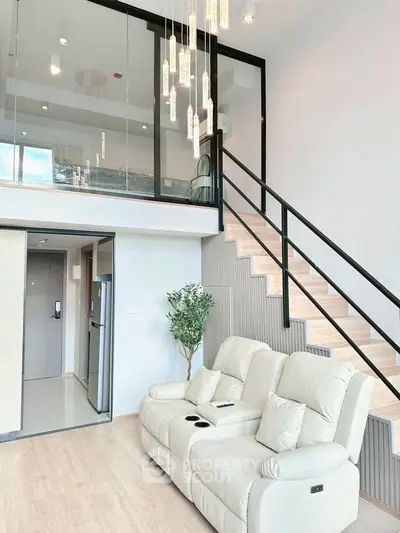 Modern duplex living room with elegant staircase and plush seating in a stylish apartment.