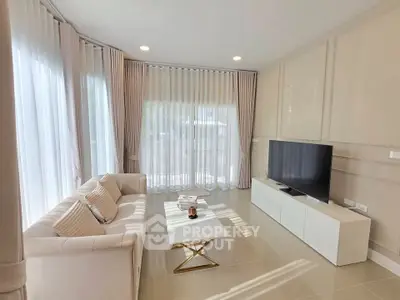 Elegant living room with modern decor, featuring a sleek TV unit and plush sofa, bathed in natural light.