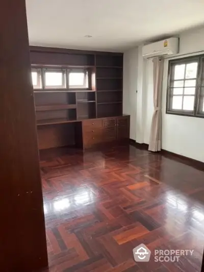 Spacious study room with wooden flooring and built-in shelves