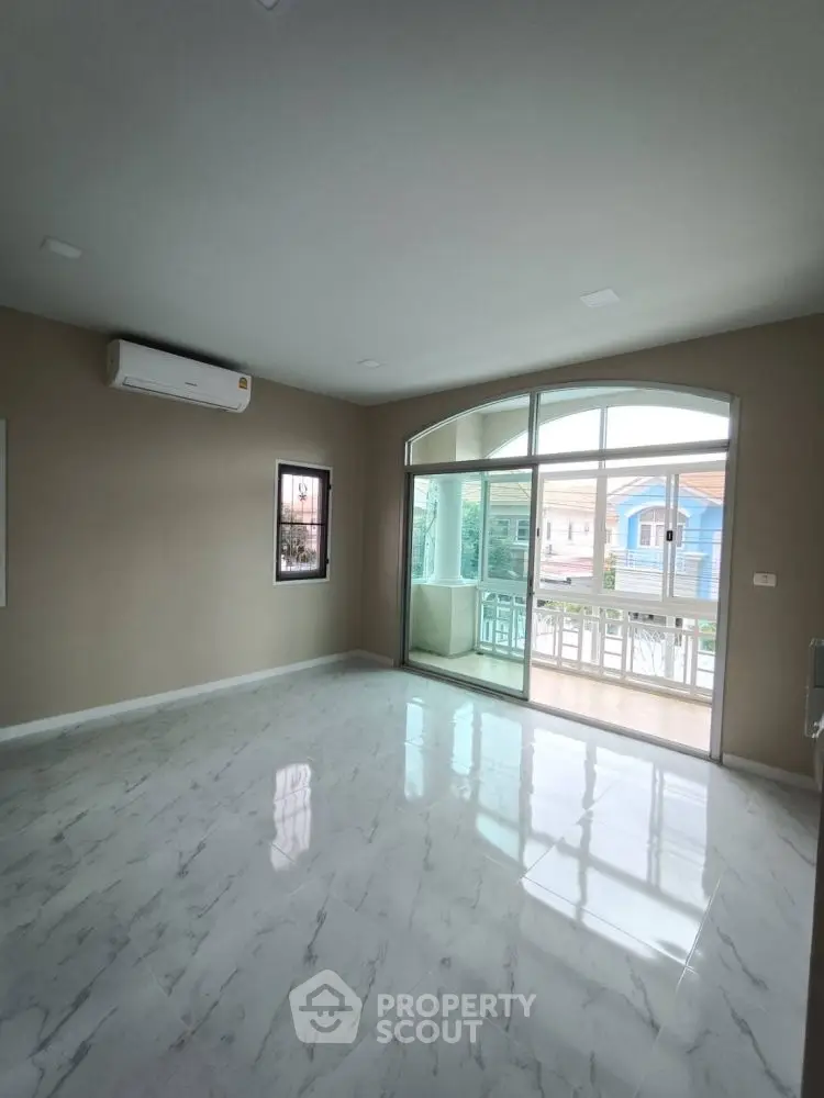 Spacious empty room with marble flooring and large window leading to balcony