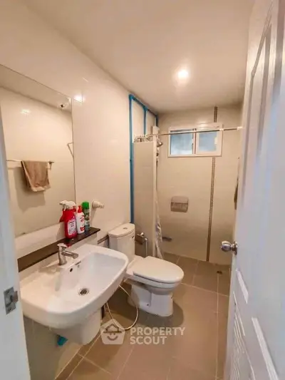 Modern bathroom with sleek fixtures and neutral tiles, featuring a compact layout.