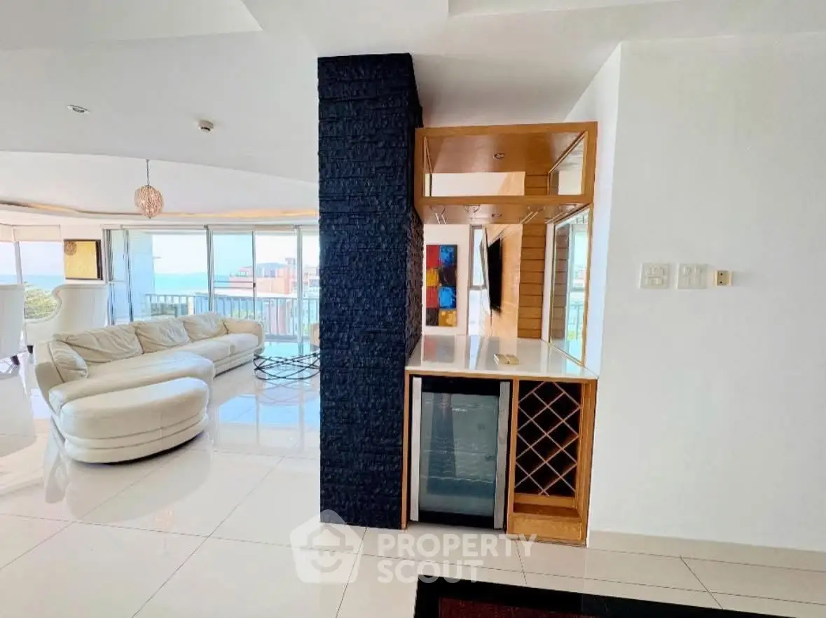 Luxurious living room with modern design and stunning ocean view, featuring elegant furniture and a mini bar.
